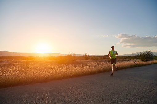 triathlon athlete running on morning training sunrise in the background